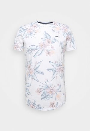 Weißes T-Shirt mit kurzen Ärmeln, pastellfarbenem tropischem Blumenmuster und kleinem schwarzem Vogel-Logo auf der linken Brust.