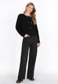 Zwarte fuzzy cropped cardigan met gouden knopen, gecombineerd met hoge taille zwarte wijde broek. Eenvoudig ontwerp met een gestructureerde afwerking.