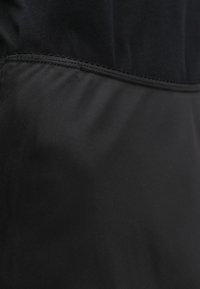 Tecido preto com textura suave e detalhes de costura. O design é simples, sem padrões ou acentuações adicionais.