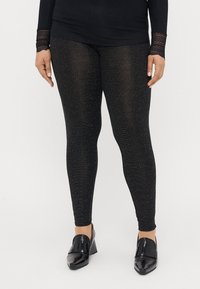 Juodos leggingai, pagaminti iš struktūrinio audinio su subtiliais blizgančiais akcentais. Derinami su blizgiais juodais aukštakulniais šlepetėmis.