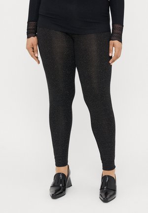 Melnas leginses, izgatavotas no strukturēta materiāla ar smalkiem mirdzošiem akcentiem. Apvienotas ar spīdīgām melnām papēža kurpēm.