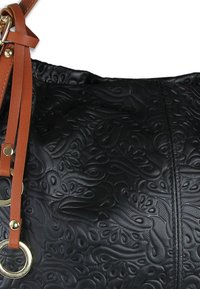 Zwarte leren tas met reliëf en ingewikkelde, kronkelende patronen, aangevuld met een bruine riem en gouden hardwaredetails.