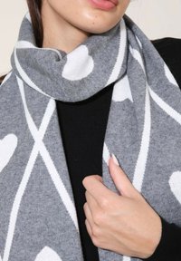 Écharpe grise avec un motif de cœur blanc et de rayures diagonales, texture douce, conçue pour s'enrouler autour du cou pour chaleur et style.