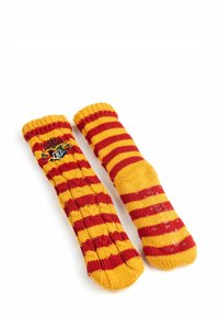 Calze a maglia a strisce rosse e gialle con un polsino a coste. Presenta un dettaglio con stemma su una calza. Tessuto morbido e vestibilità comoda.