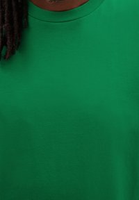 Zelené bavlněné tričko s kulatým výstřihem a krátkými rukávy. Hladká textura, žádné viditelné vzory ani akcenty. Jednoduchý, ležérní design.