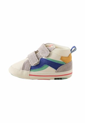 Child's beige sneaker with blue and green accents, two gray velcro straps, textured sole, and a yellow heel patch with a blue pull tab.