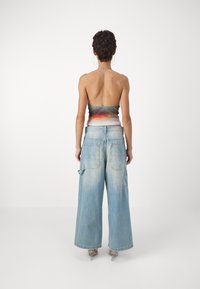 Top bez ramínek v mnoha barvách, spárovaný s volnými světle modrými džíny, které mají boční kapsy a vybledlý vzhled.