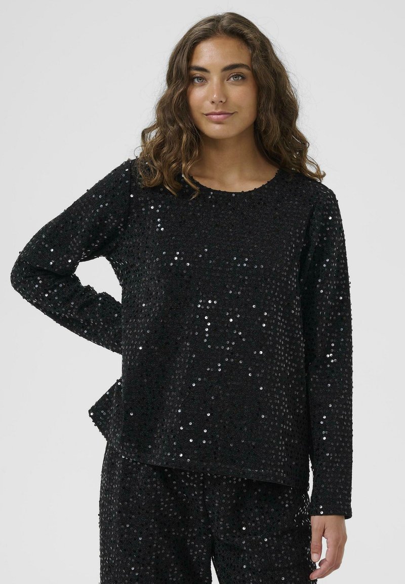 Maglietta nera a maniche lunghe con vestibilità ampia, ricoperta di paillettes brillanti, con scollatura rotonda e orlo piatto, abbinata a pantaloni coordinati.