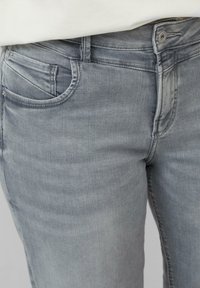 Lichtgrijze denim jeans met een slim fit ontwerp, voorzien van een subtiele stretch, voorzakdetails en een standaard metalen knoopsluiting.