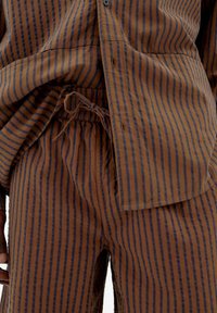 Brown striped shirt and pants set with navy vertical stripes. Lightweight fabric, relaxed fit, featuring a drawstring waist and button details.