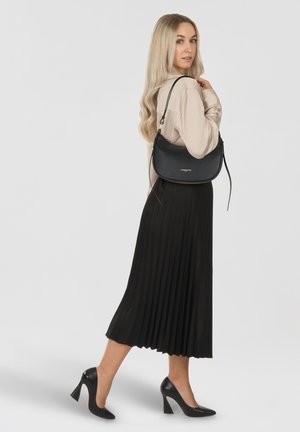 Sac en cuir noir à bandoulière avec une finition texturée, associé à une longue jupe plissée noire et des chaussures à talons hauts noires. Détails de design simples.