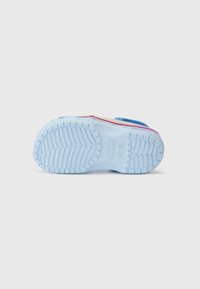 Des Crocs multicolores avec une semelle extérieure texturée bleue. Elles sont dotées de rainures pour une meilleure adhérence, avec des couleurs d'accent rose, jaune et bleu sur le dessus.