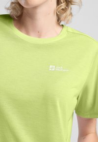 Maglietta a maniche corte verde brillante realizzata in un morbido e traspirante tessuto. Presenta un piccolo logo bianco sulla parte superiore sinistra del petto.