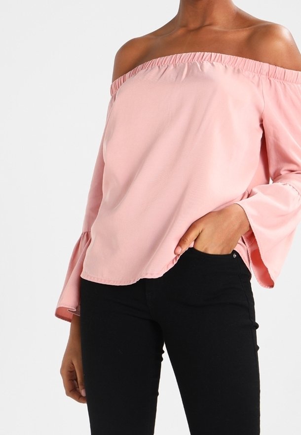 Blusa rosa off-shoulder con scollatura arricciata e maniche a campana, abbinata a pantaloni neri aderenti. Tessuto liscio, tessuto leggero.