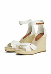Sandalias de cuña blancas con suela de yute trenzada, tiras de lona y un detalle de hebilla marrón en la correa del tobillo. Suela interior plana.