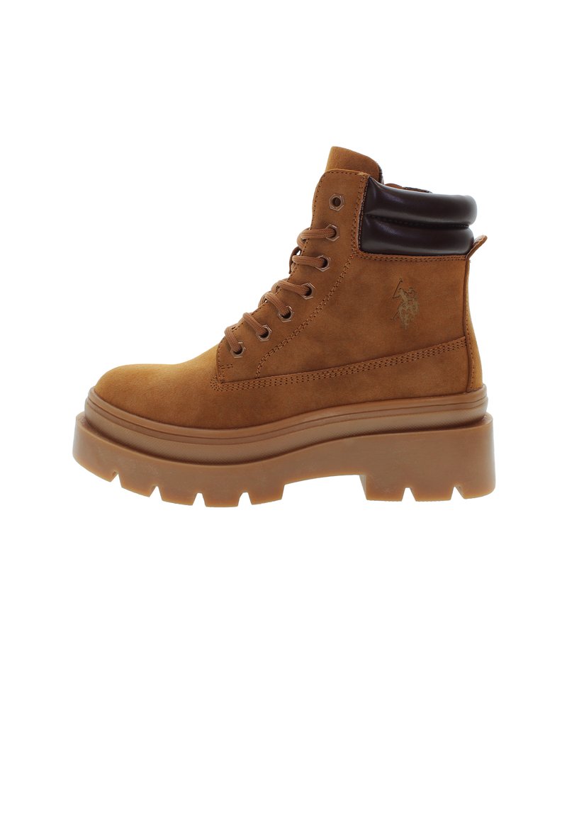 Stivale alla caviglia in suede marrone con suola spessa e texturizzata, punta arrotondata e collo imbottito. Presenta occhielli in metallo e dettaglio del logo sul lato.