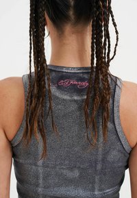 Šedý bezrukávový top s žebrovanou texturou, na zadní straně s růžovou výšivkou "Ed Hardy".