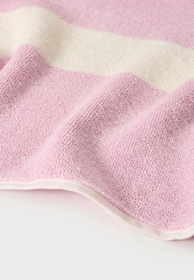 Serviette à texture douce avec des rayures horizontales roses et blanches, légèrement pliée sur une surface blanche.
