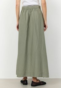 Falda maxi en verde oliva, fabricada con tela ligera. Presenta una cinturilla elástica y un diseño fluido que llega hasta los tobillos.