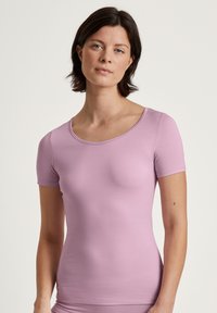 Top aderente a maniche corte realizzato in tessuto morbido e elasticizzato di un delicato color lavanda. Presenta un collo rotondo e polsini senza cuciture.
