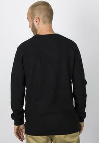 Schwarzer Sweatshirt mit langen Ärmeln, Rundhalsausschnitt und lockerer Passform. Sichtbare Nähte und gerippte Bündchen. Glatte Textur.