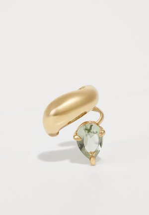 Anillo de metal dorado con una banda smooth y curva, y un engaste de piedra preciosa verde en forma de pera a un lado. Acabado pulido, sin patrones visibles.