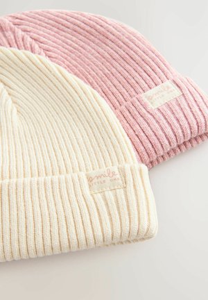 Zwei gestrickte Mützen: eine in Creme und eine in Hellrosa. Beide haben eine gerippte Textur und ein kleines Etikett mit "smile" an den Bündchen.