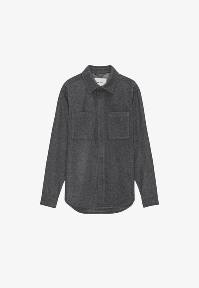 Grå flanellskjorta med knäppning framtill, två bröstfickor, långa ärmar, spetsig krage och rundad fåll. Strukturerad kvalité med mjuk yta.