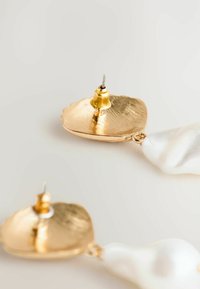 Orecchino a forma di conchiglia in oro con superficie testurizzata, dotato di una goccia di perla bianca. Include un perno dorato per indossarlo.