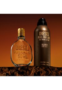 Dwa produkty Diesel Fuel For Life: szklana butelka perfum o pojemności 50 ml z złotą zakrętką i brązowy dezodorant w sprayu do ciała na teksturowanej powierzchni.