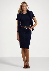 Mornarska majica slojevito nošena ispod mornarskog džempera s pletenim uzorkom, u kombinaciji s uskom traper suknjom. Smeđi remen sa zlatnom kopčom, smeđe mokasinke.