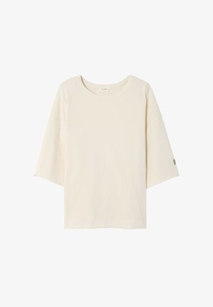 Tričko krémovej farby s okrúhlym výstrihom, krátkymi dolmánovými rukávmi a malým zeleným logom na ľavom rukáve. Mäkká, ľahká látka.