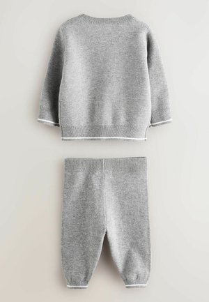Grijze gebreide trui en broek set met ribbelaccenten. De trui heeft een ronde hals en lange mouwen; de broek heeft taps toelopende manchetten.