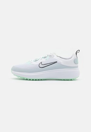 Baskets Nike blanches et gris clair avec un logo swoosh noir, fermeture à lacets, semelle épaisse et semelle extérieure texturée vert clair.