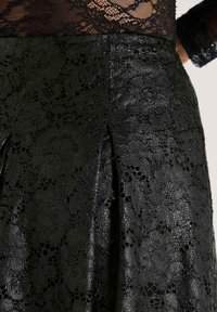Zwarte kant rok met bloemenpatronen, een gestructureerde afwerking en een geplooid ontwerp. De gladde stof met ingewikkelde details verhoogt de visuele aantrekkingskracht.