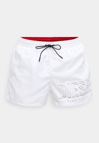 Valged ujumispüksid sünteetilisest materjalist, millel on must pingutusnöör, punane sisemüür ja küljes reljeefne "DIESEL" brändi tähistus.