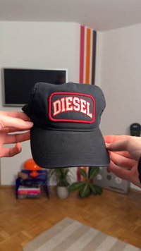 Μαύρο καπέλο με κόκκινη ταμπέλα "DIESEL" στο μπροστινό μέρος. Διαθέτει κυρτό γείσο και δίχτυ στα πλαϊνά. Διακρίνονται επίπεδες ραφές.