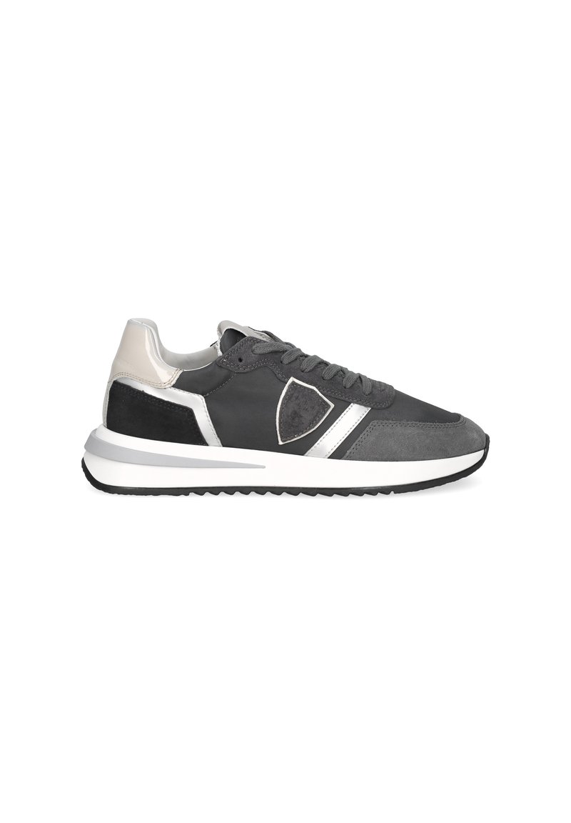 Men's low-top sneaker in black, grey, white, and beige with lace-up front and shield-shaped logo on side.