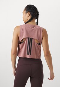 Rosa crop top med udsnit i ryggen og tre sorte striber. Blødt materiale kombineret med mørkebrune højtaljede leggings.