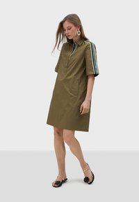Khaki shirt dress with short sleeves, front zip, and side pockets; features multicolored stripes on sleeves; smooth, lightweight fabric.