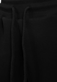Sorte sweatpants lavet af blødt bomuldsblandingsstof. Har en ribbet talje og matchende snor, samt sidelommer og en glat overflade.