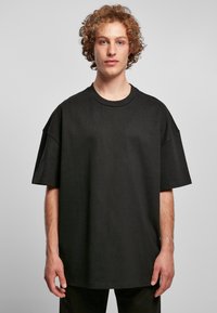 Zwart oversized t-shirt van katoen, met een ronde halslijn en korte mouwen, een gladde textuur en minimale stikseldetails.