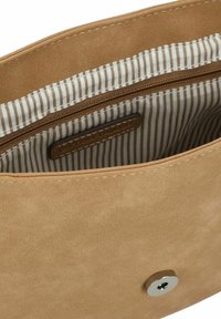Helle, kunstleder Handtasche in Tan mit einem Reißverschlussfach innen, ausgestattet mit einem gestreift gefütterten Innenraum und einem Druckverschluss mit silbernem Akzent.