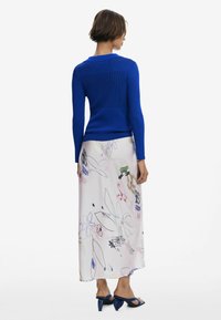 Ribbed blue top paired with a flowing, floral patterned skirt in light shades and blue heeled sandals. Back view highlights design elements.
