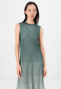 Sleeveless green dress with vertical pleats, featuring a plain round neckline and a slightly tapered shape, made from a textured fabric.