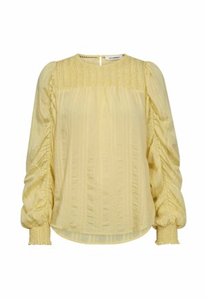 Žuta bluza s dugim naboranim rukavima, detaljima na ramenima i manžetama te teksturom okomitim prugama. Zakopčavanje na stražnjoj strani s otvorom u obliku ključa.