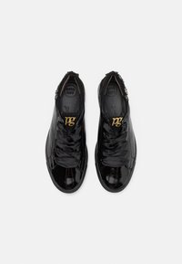 Paire de baskets en cuir noir brillant avec de larges lacets en satin noir et logo doré "pg" sur la languette, vues de dessus sur fond blanc.