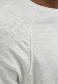 Maglione a maglia grigio chiaro con una cucitura testurizzata e colletto a coste. Il tessuto sembra morbido e traspirante, con una vestibilità leggermente ampia.