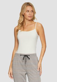 Witte, strak aangesloten tanktop met dunne schouderbandjes, gecombineerd met geruite jogpants met trekkoord en zwarte accenten van gestructureerde stof.