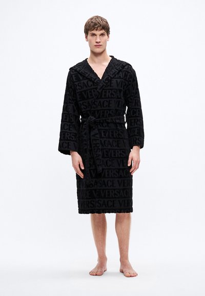 Čierny župan s plyšovou textúrou, zavinovacím dizajnom a vyrazeným vzorom "VERSACE". Obsahuje opasok na viazanie a dlhé rukávy.